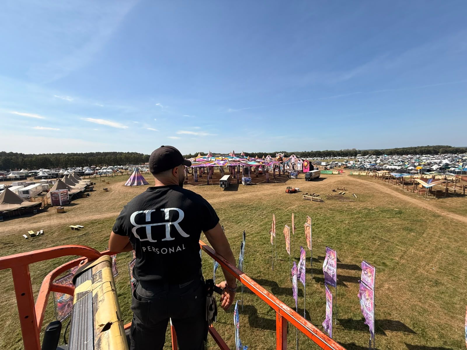 Blick von einer Hebebühne über ein Festivalgelände mit Zelten, Fahnen und großer Bühne