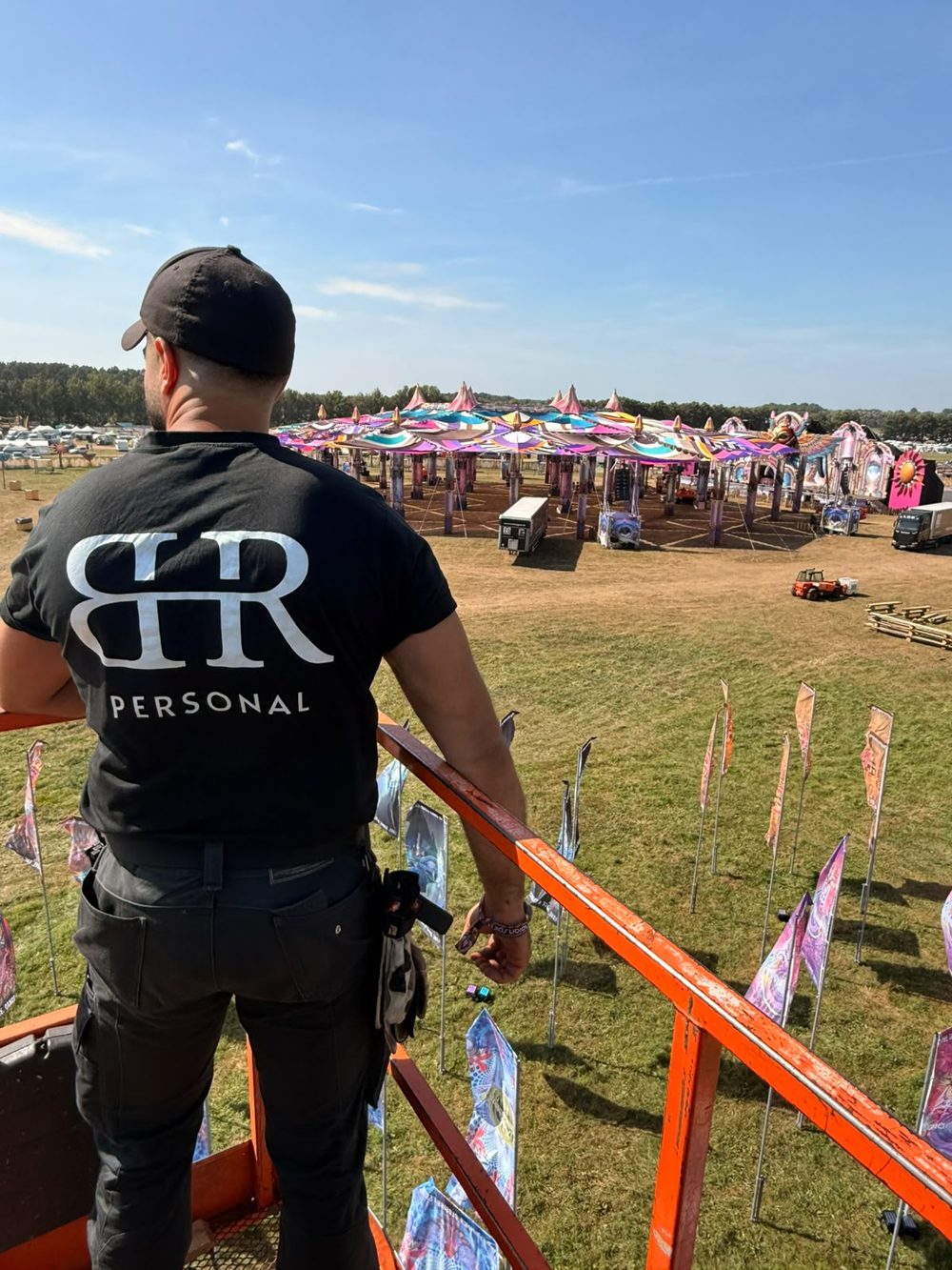 Mitarbeiter von BR Personal im schwarzen T-Shirt mit Logo auf einer Hebebühne, Blick über ein Festivalgelände mit großer Bühne